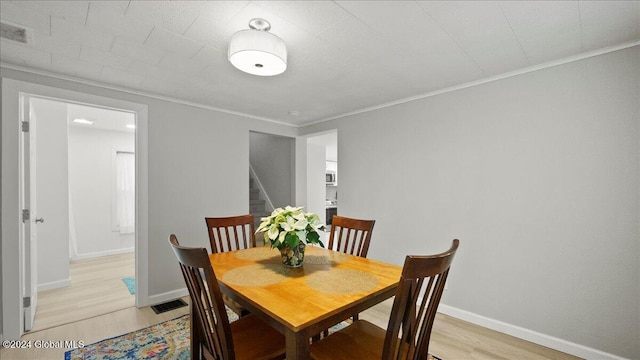 dining room with light hardwood / wood-style floors and ornamental molding