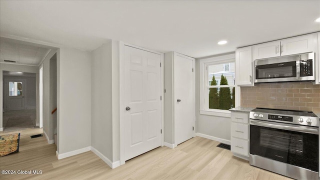 kitchen with white cabinets, stainless steel appliances, light hardwood / wood-style flooring, and tasteful backsplash