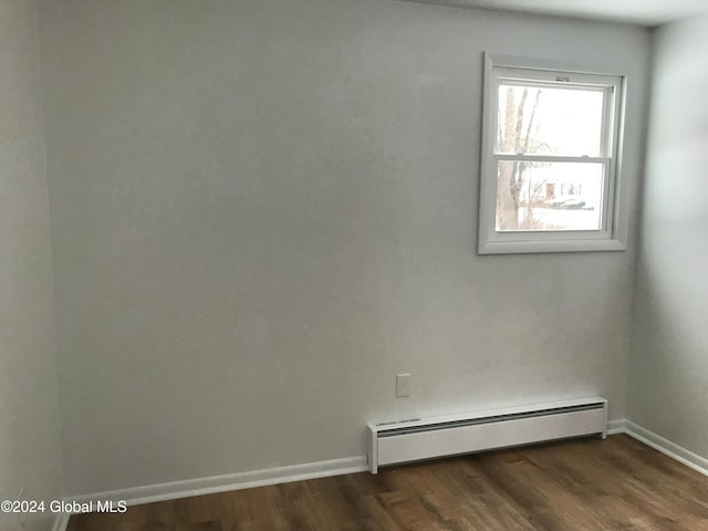 unfurnished room featuring dark wood-type flooring and a baseboard radiator