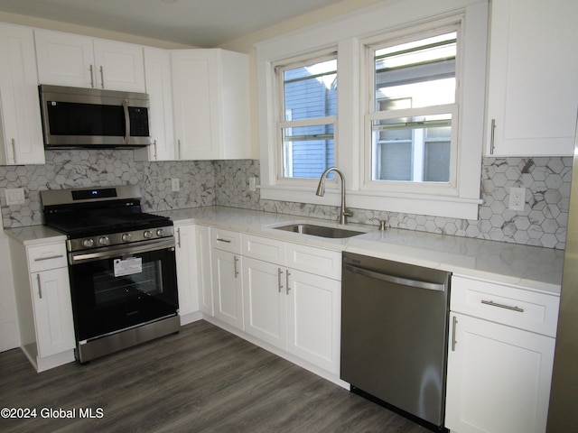 kitchen featuring appliances with stainless steel finishes, light stone counters, dark wood-type flooring, sink, and white cabinets