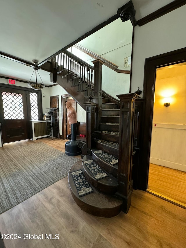 stairway with hardwood / wood-style flooring and crown molding