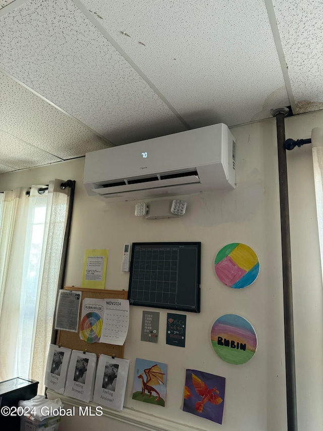 interior space with an AC wall unit and a paneled ceiling