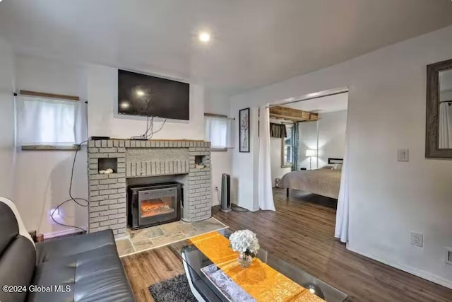 living room with a brick fireplace and hardwood / wood-style flooring