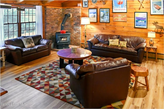 living room featuring hardwood / wood-style flooring, a wood stove, and wooden walls