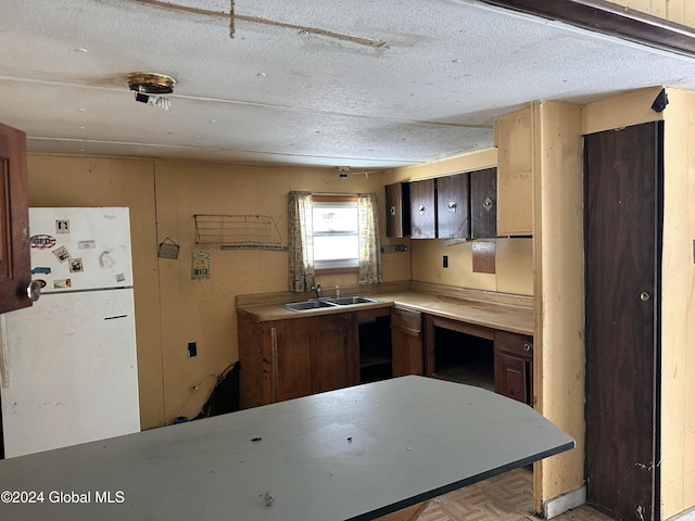 kitchen featuring a textured ceiling, white fridge, light parquet floors, and sink