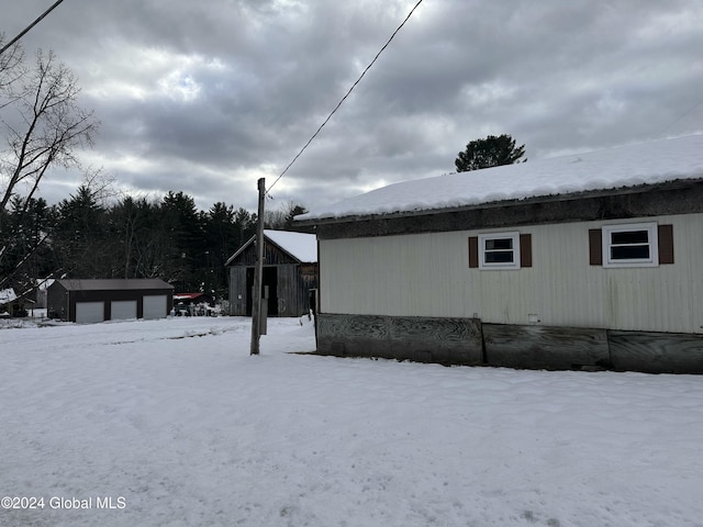 view of snowy exterior featuring an outbuilding and a garage