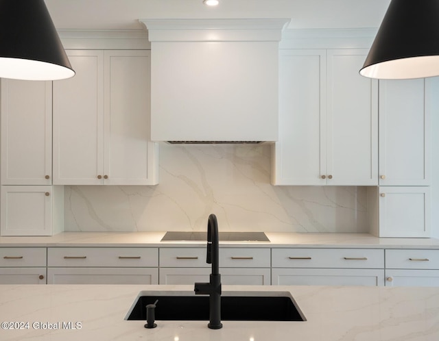 kitchen featuring light stone countertops, sink, black electric cooktop, decorative backsplash, and white cabinets