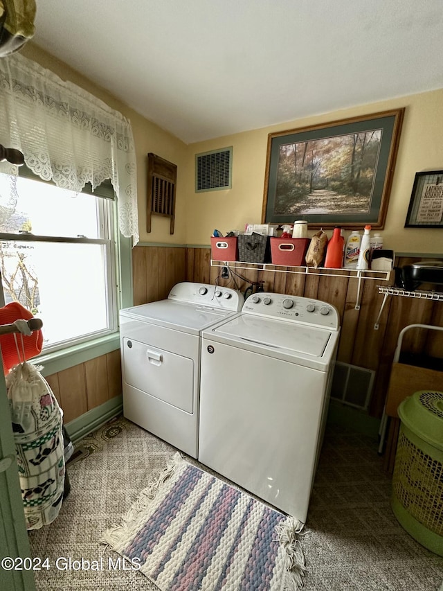 laundry room with carpet, independent washer and dryer, and wooden walls