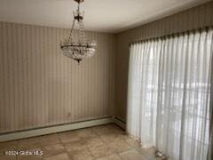 unfurnished dining area with a chandelier and a baseboard radiator