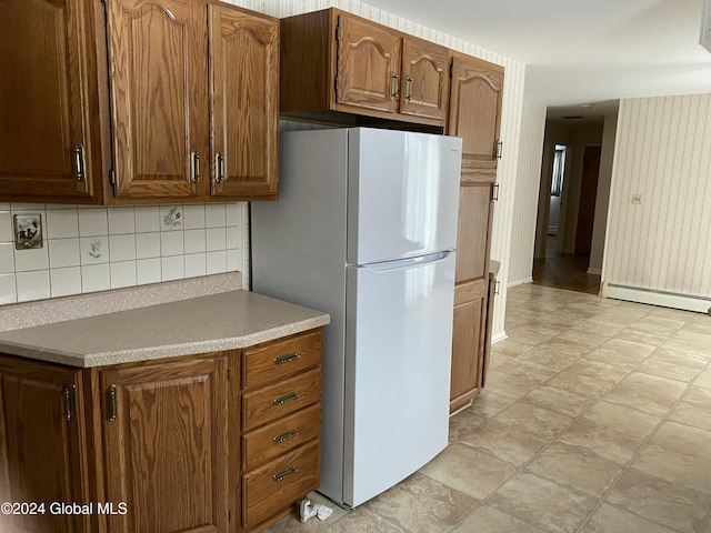 kitchen with white refrigerator, backsplash, and a baseboard radiator