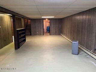 basement featuring a paneled ceiling and wood walls