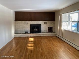 unfurnished living room with hardwood / wood-style floors and baseboard heating