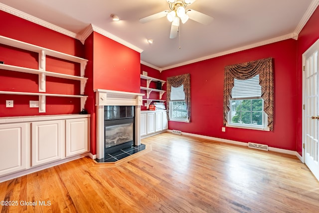 unfurnished living room featuring a fireplace, light wood-type flooring, ceiling fan, and crown molding