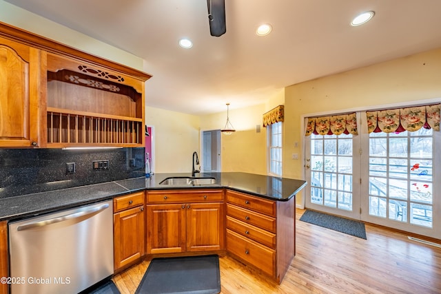 kitchen featuring dishwasher, sink, light hardwood / wood-style flooring, kitchen peninsula, and pendant lighting