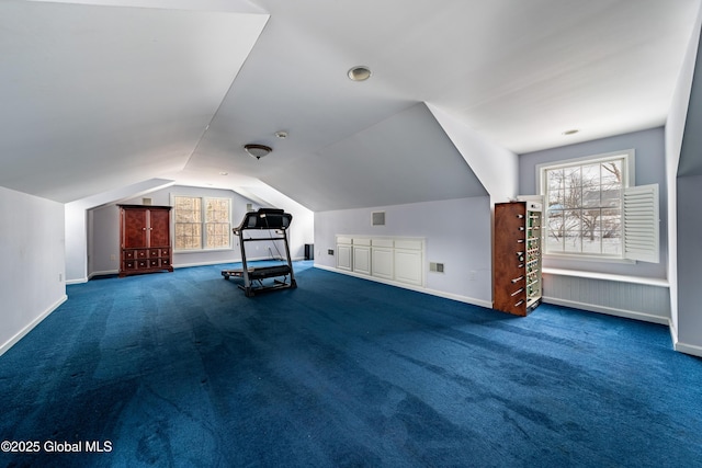 bonus room with dark colored carpet and lofted ceiling