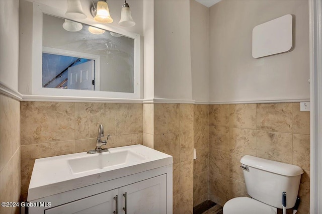 bathroom with vanity, toilet, and tile walls