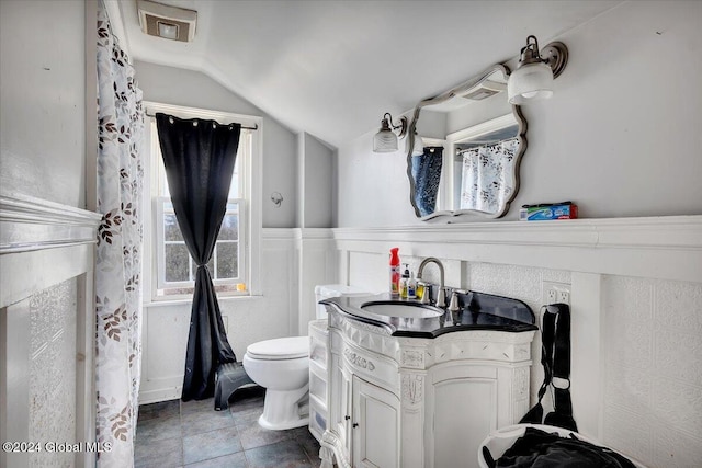 bathroom featuring tile patterned flooring, vanity, toilet, and lofted ceiling