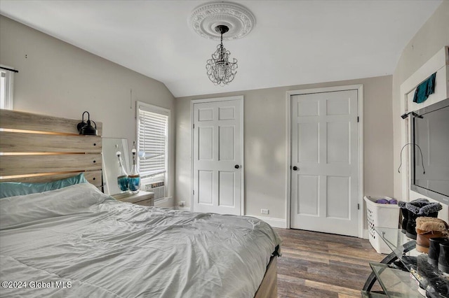 bedroom featuring dark hardwood / wood-style flooring, lofted ceiling, and a notable chandelier