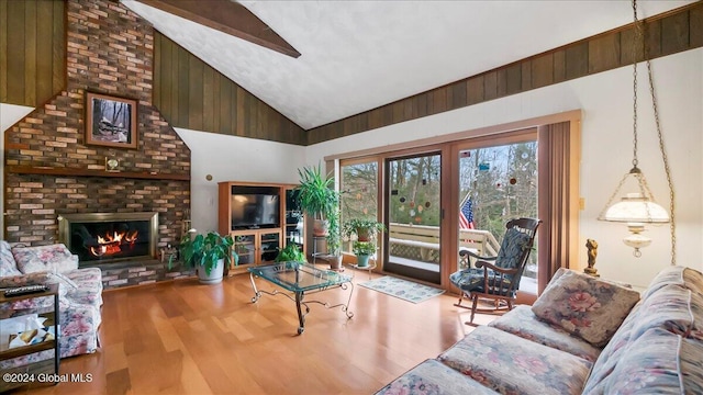 living room featuring wooden walls, a fireplace, high vaulted ceiling, and hardwood / wood-style flooring