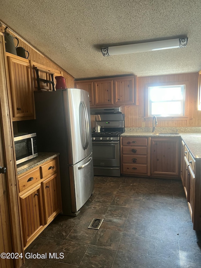 kitchen with visible vents, a textured ceiling, stainless steel appliances, and lofted ceiling