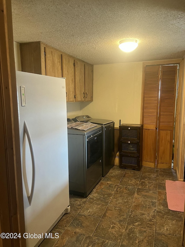 washroom with cabinet space, a textured ceiling, and independent washer and dryer