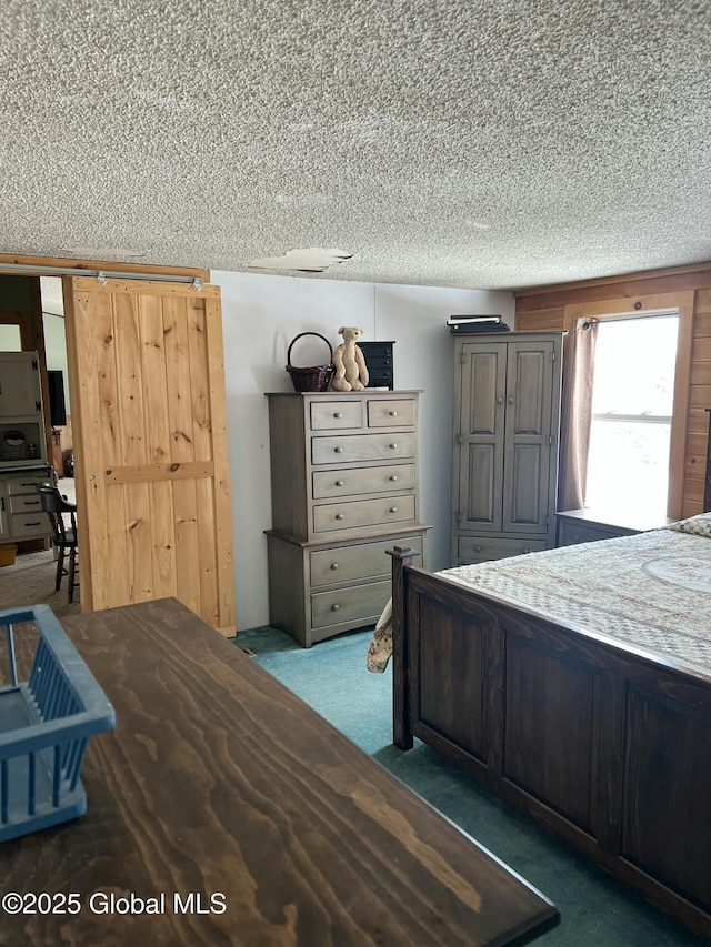 unfurnished bedroom featuring a textured ceiling, a barn door, and carpet floors