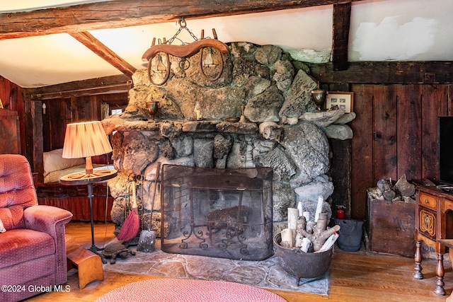 room details featuring hardwood / wood-style floors, wooden walls, a fireplace, and beamed ceiling