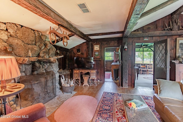 living room featuring vaulted ceiling with beams, wood walls, and light hardwood / wood-style floors