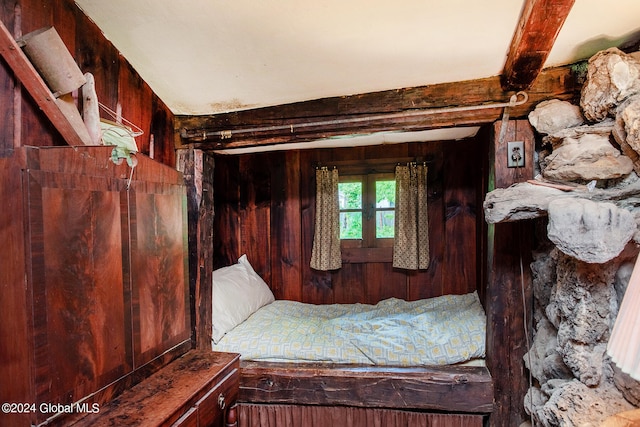 unfurnished bedroom featuring beam ceiling and wooden walls