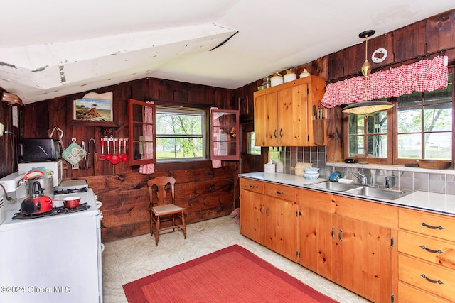 kitchen with backsplash, wooden walls, sink, and hanging light fixtures