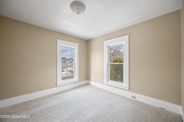 carpeted spare room with a textured ceiling