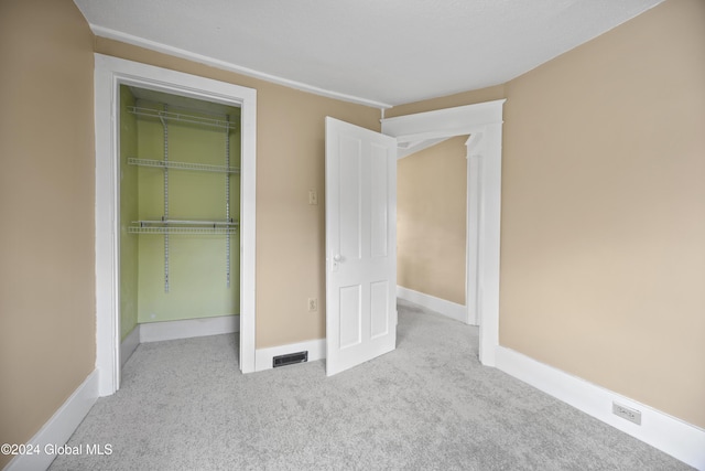 unfurnished bedroom featuring light carpet and a closet