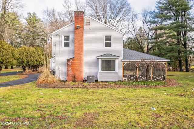 view of side of home with central air condition unit, a lawn, and a sunroom