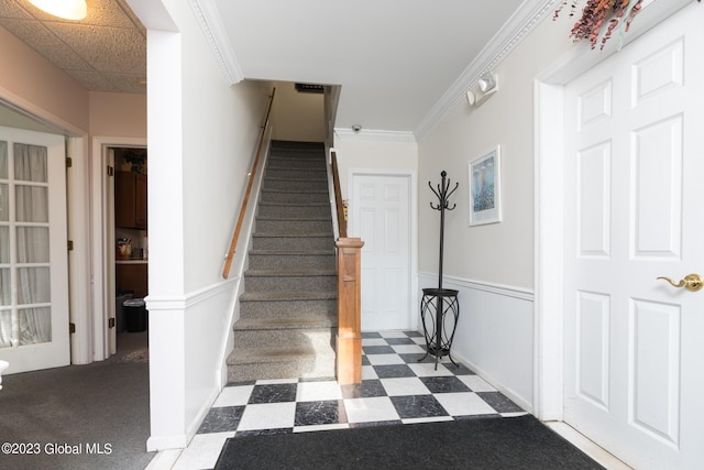 staircase featuring a paneled ceiling, carpet floors, and ornamental molding