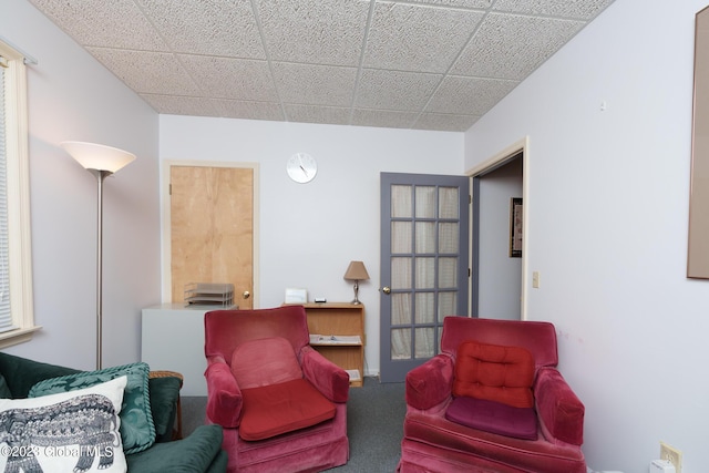 living area with carpet flooring and a drop ceiling