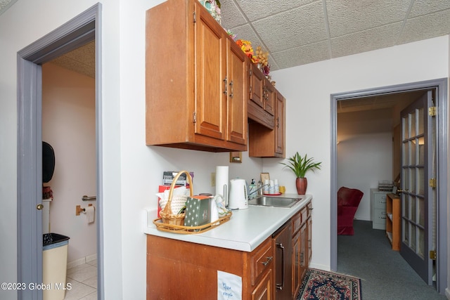 kitchen featuring a paneled ceiling, light colored carpet, and sink