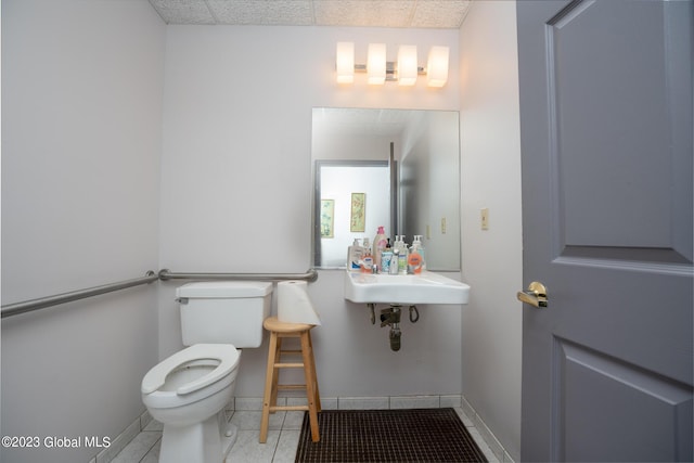 bathroom with tile patterned flooring, toilet, a drop ceiling, and sink