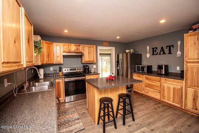 kitchen featuring sink, a kitchen breakfast bar, appliances with stainless steel finishes, a kitchen island, and hardwood / wood-style flooring