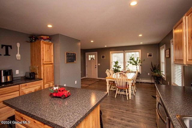 kitchen with a center island, dark wood-type flooring, a baseboard radiator, stainless steel dishwasher, and light brown cabinetry