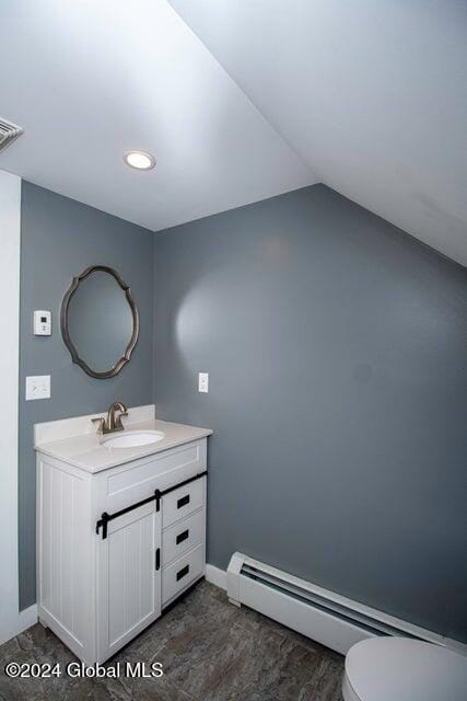 bathroom with baseboard heating, vanity, vaulted ceiling, and toilet