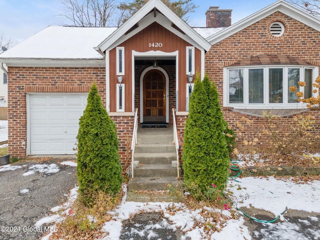 snow covered property entrance featuring a garage