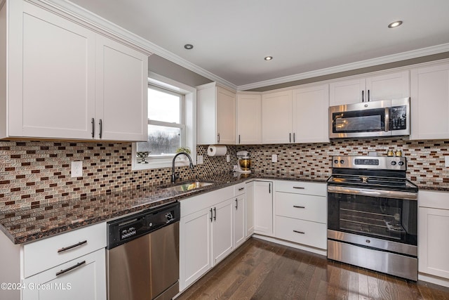 kitchen featuring appliances with stainless steel finishes, ornamental molding, dark wood-type flooring, and sink