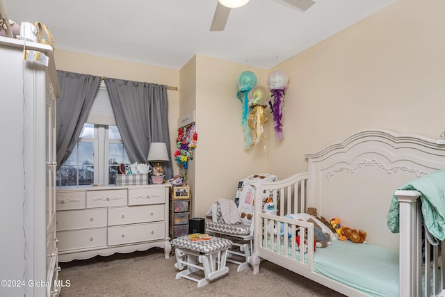 carpeted bedroom with ceiling fan and a nursery area