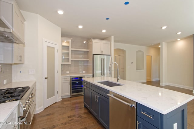 kitchen featuring beverage cooler, dark hardwood / wood-style flooring, a center island with sink, white cabinets, and appliances with stainless steel finishes