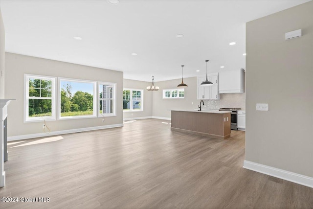 unfurnished living room featuring light hardwood / wood-style floors, a notable chandelier, and sink