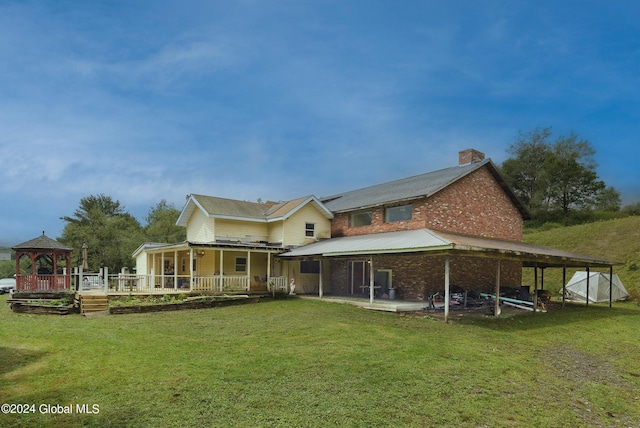 rear view of house featuring a lawn and a gazebo