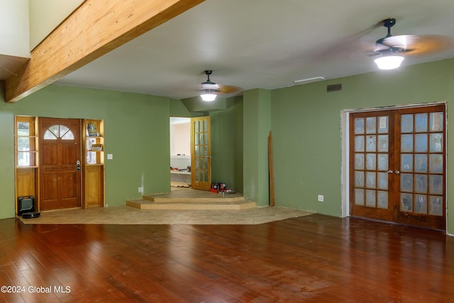 unfurnished living room with beamed ceiling, hardwood / wood-style floors, french doors, and ceiling fan