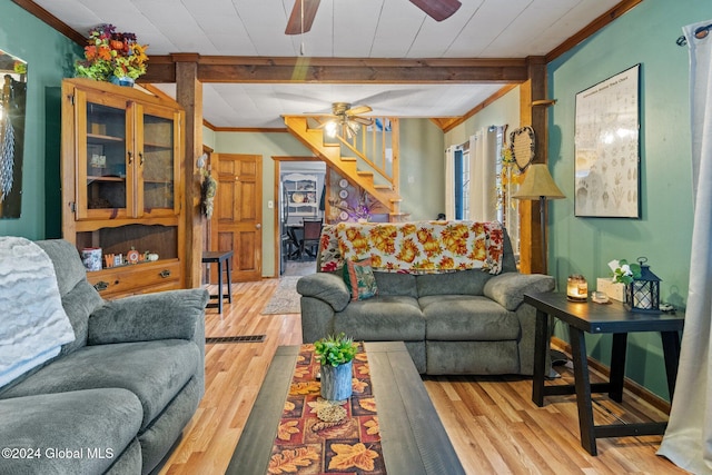 living room featuring beamed ceiling, light hardwood / wood-style floors, and crown molding