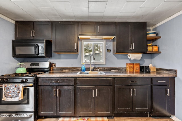 kitchen featuring gas stove, sink, dark brown cabinets, and ornamental molding