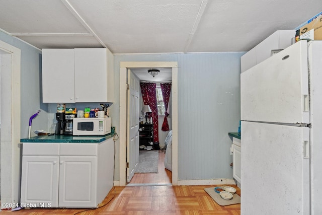 kitchen with a textured ceiling, white cabinetry, light parquet floors, and white appliances